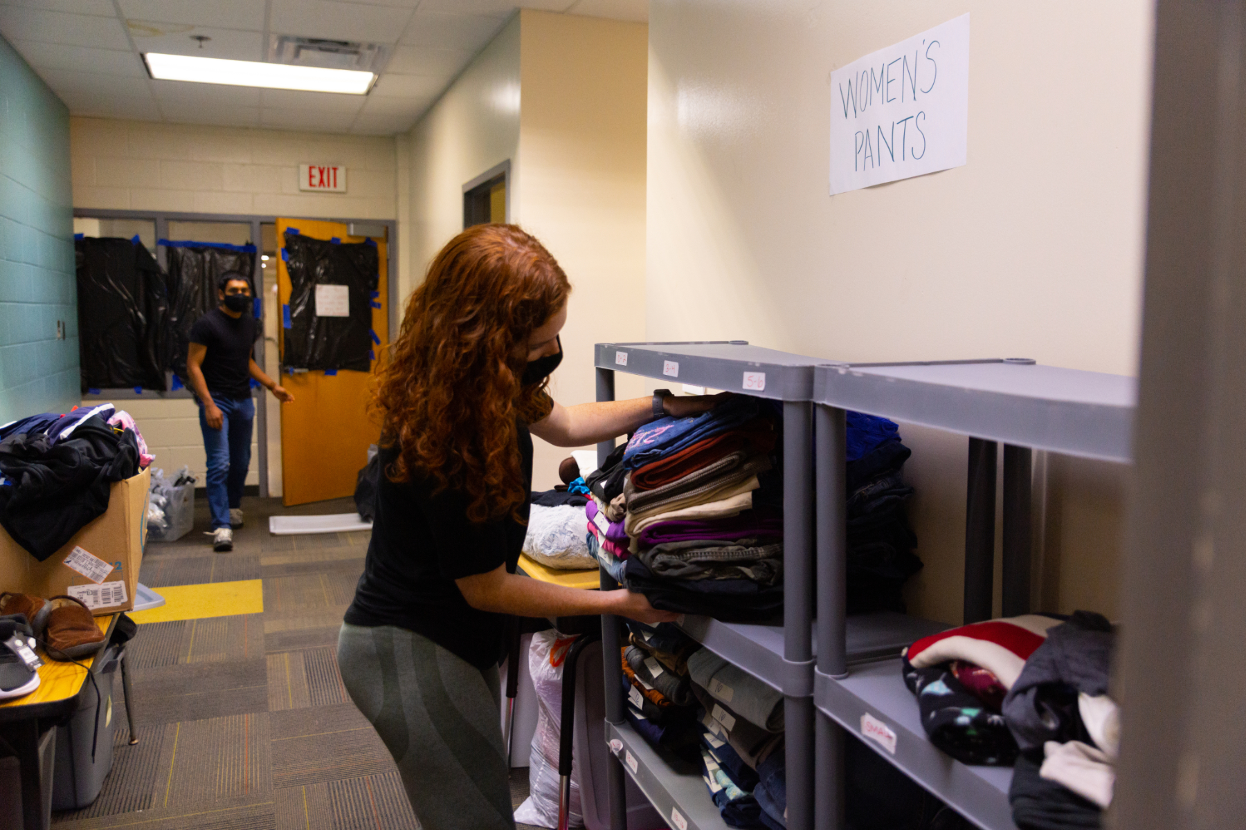 a student takes a stack of clothes off a shelf