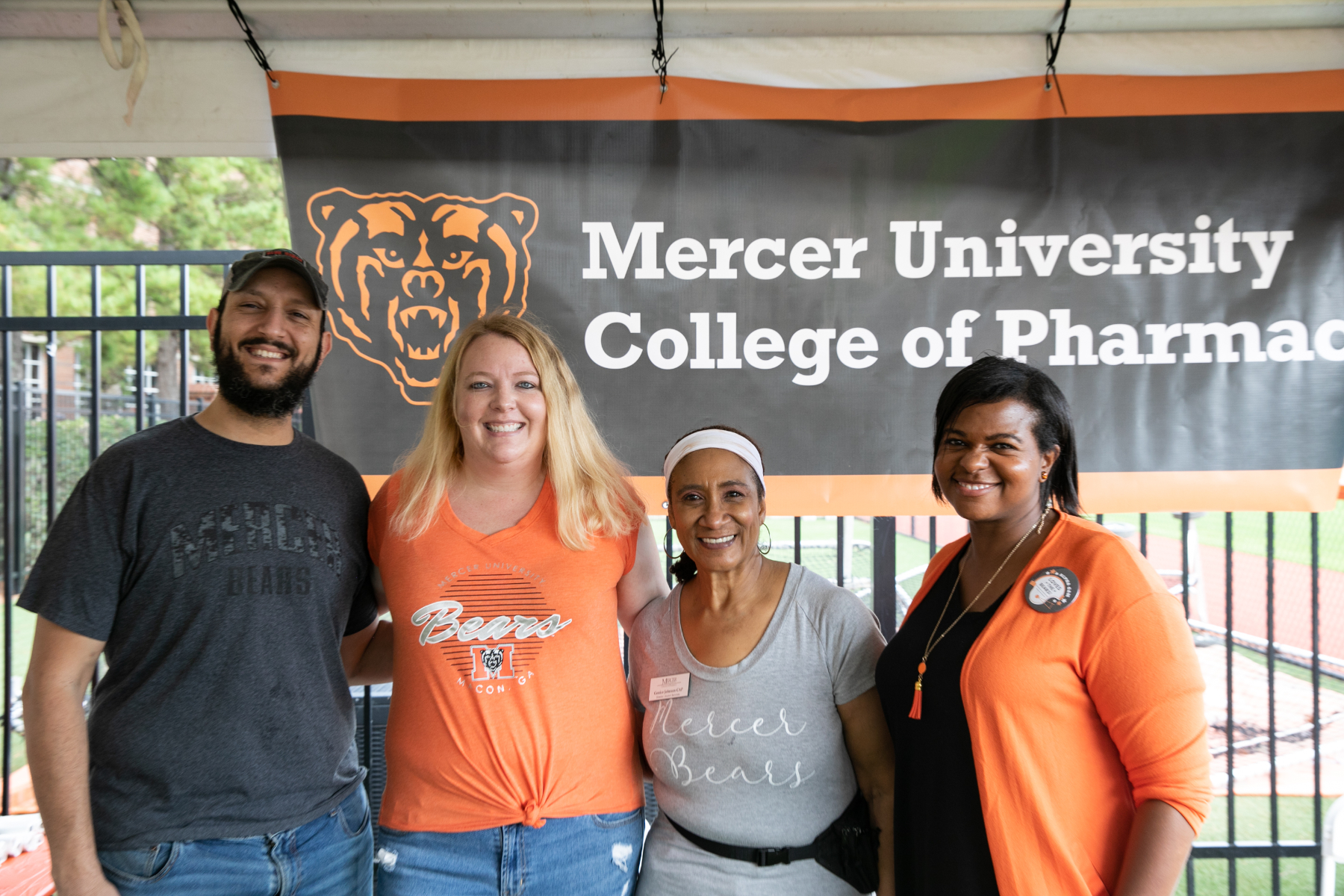 one man and three women stand in front of a mercer university college of pharmacy sign