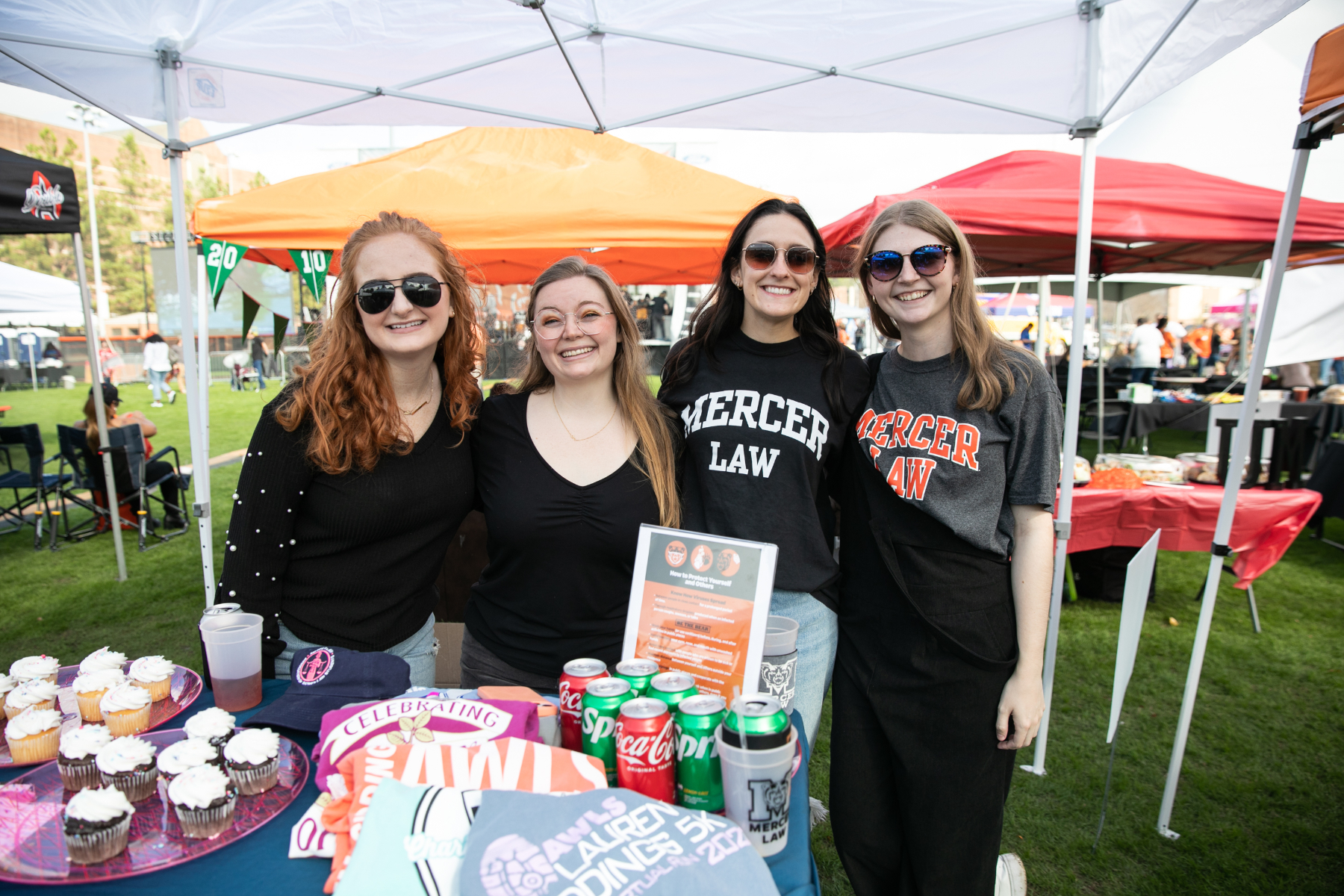 four women, two of whom are wearing mercer law t-shirts, at a tailgate