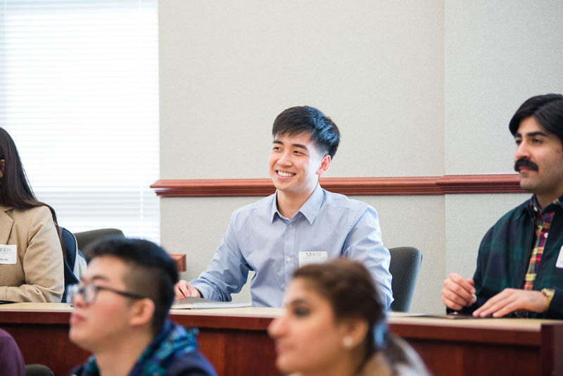 A Mercer student smiles in a classroom setting filled with other students.
