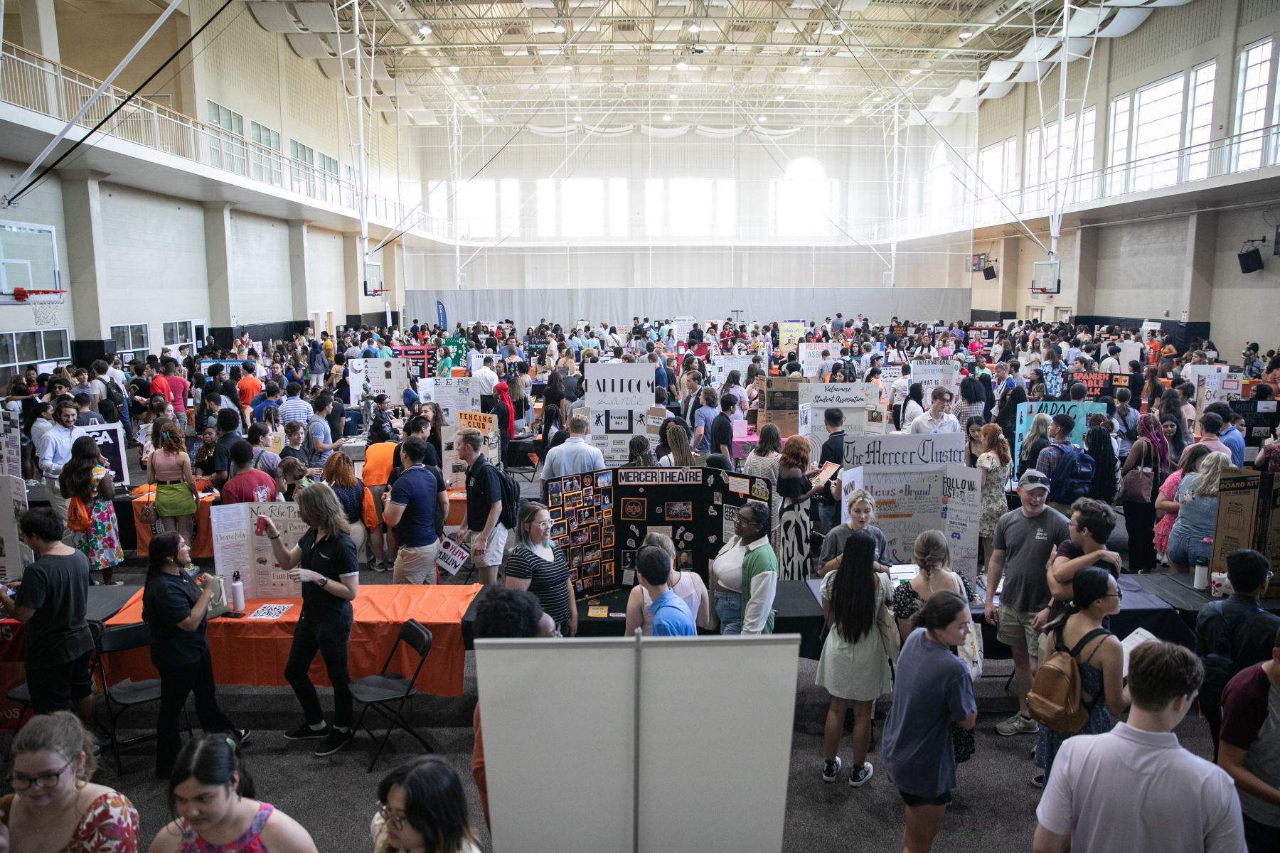 Mercer students crowd onto the intramural basketball courts in the University Center where tables are set up with trifold boards promoting various student organizations.