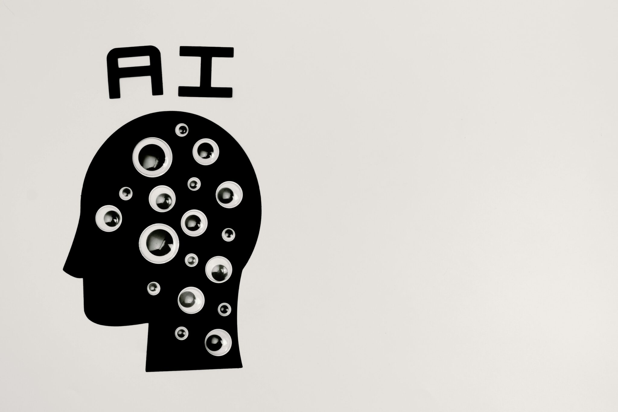 A silhouette of a head covered in googly eyes. "AI" is displayed above the head.