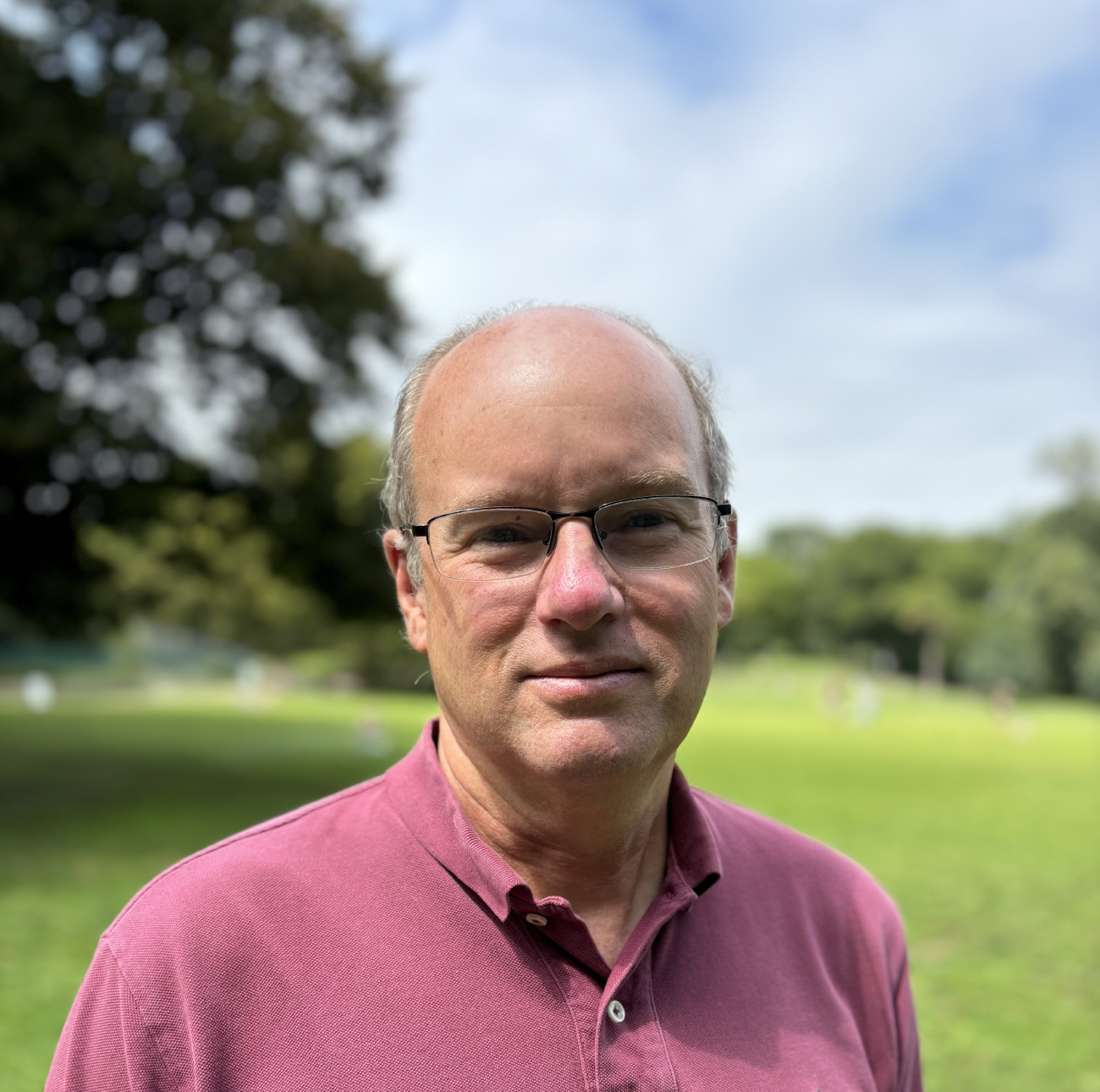 Headshot of Judson Watson wearing a maroon polo shirt outside with greenery in the background.