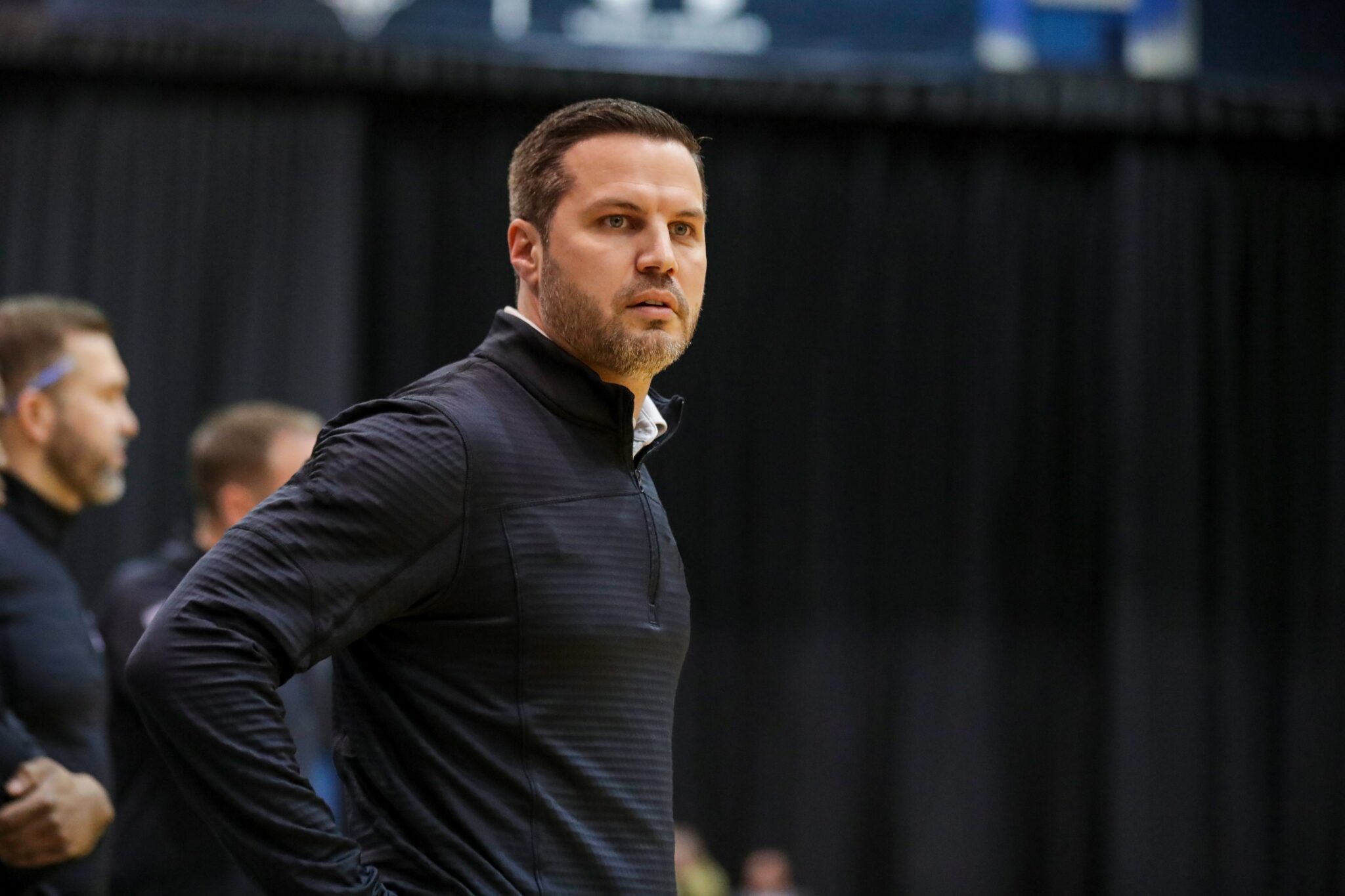 Basketball Coach Ryan Ridder wearing a black pullover on the sidelines.