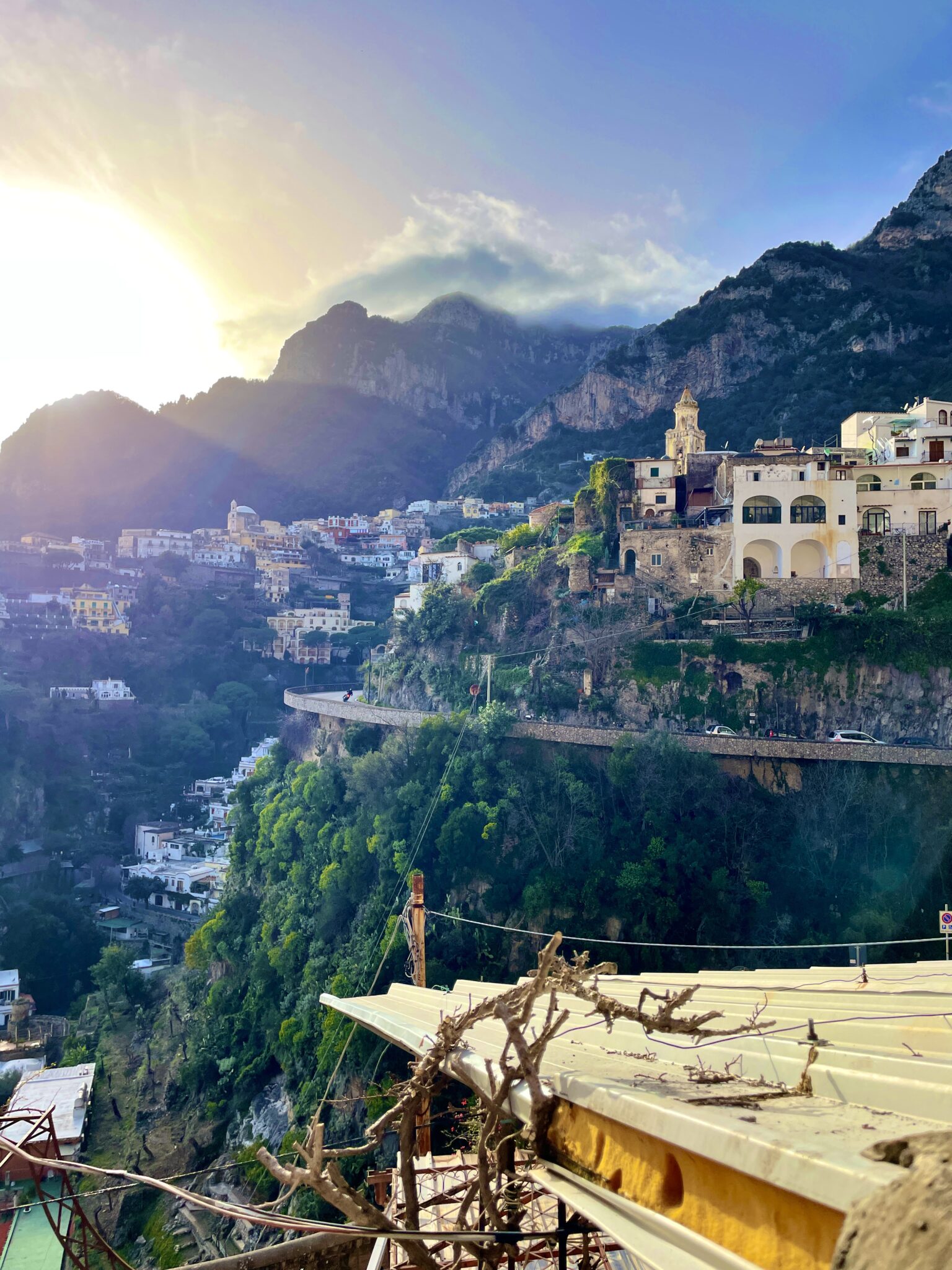 View of houses nestled in a mountainside with a sunset in the background.