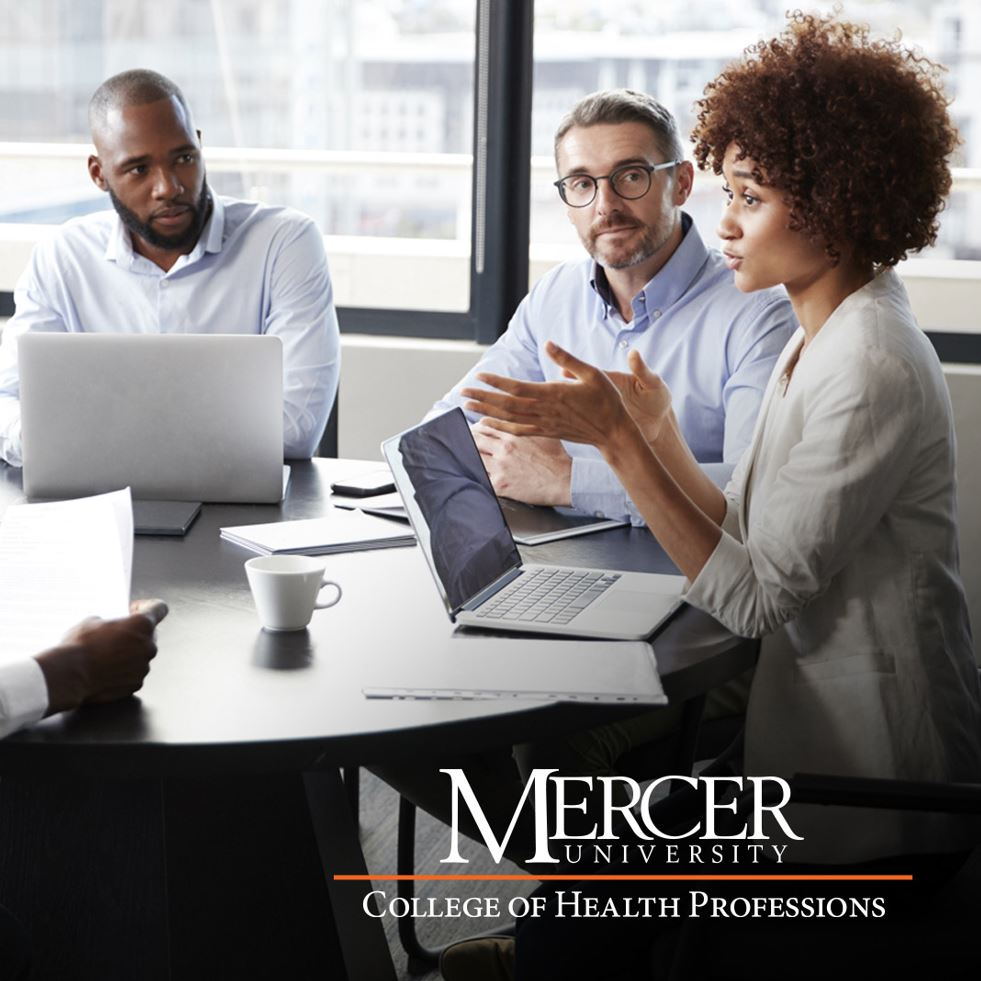 Three professionals are engaged in a meeting around a table with laptops. One person is gesturing while speaking, and the others are listening attentively. The room has large windows letting in natural light. In the bottom right corner, there's a logo for Mercer University College of Health Professions.