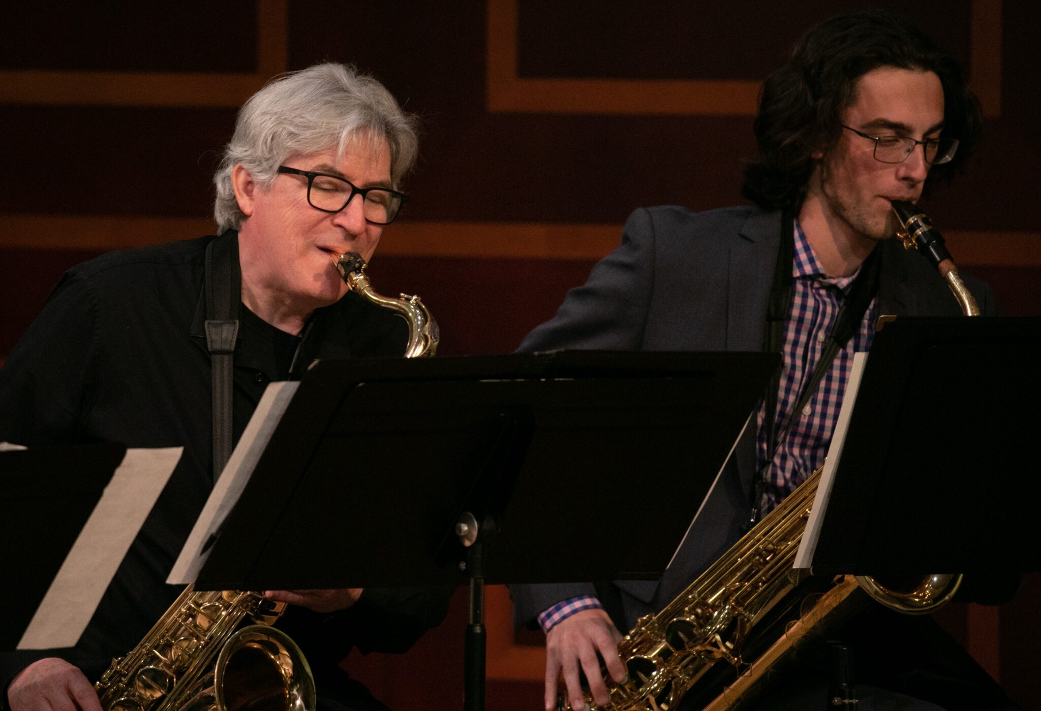 Two individuals play saxophone