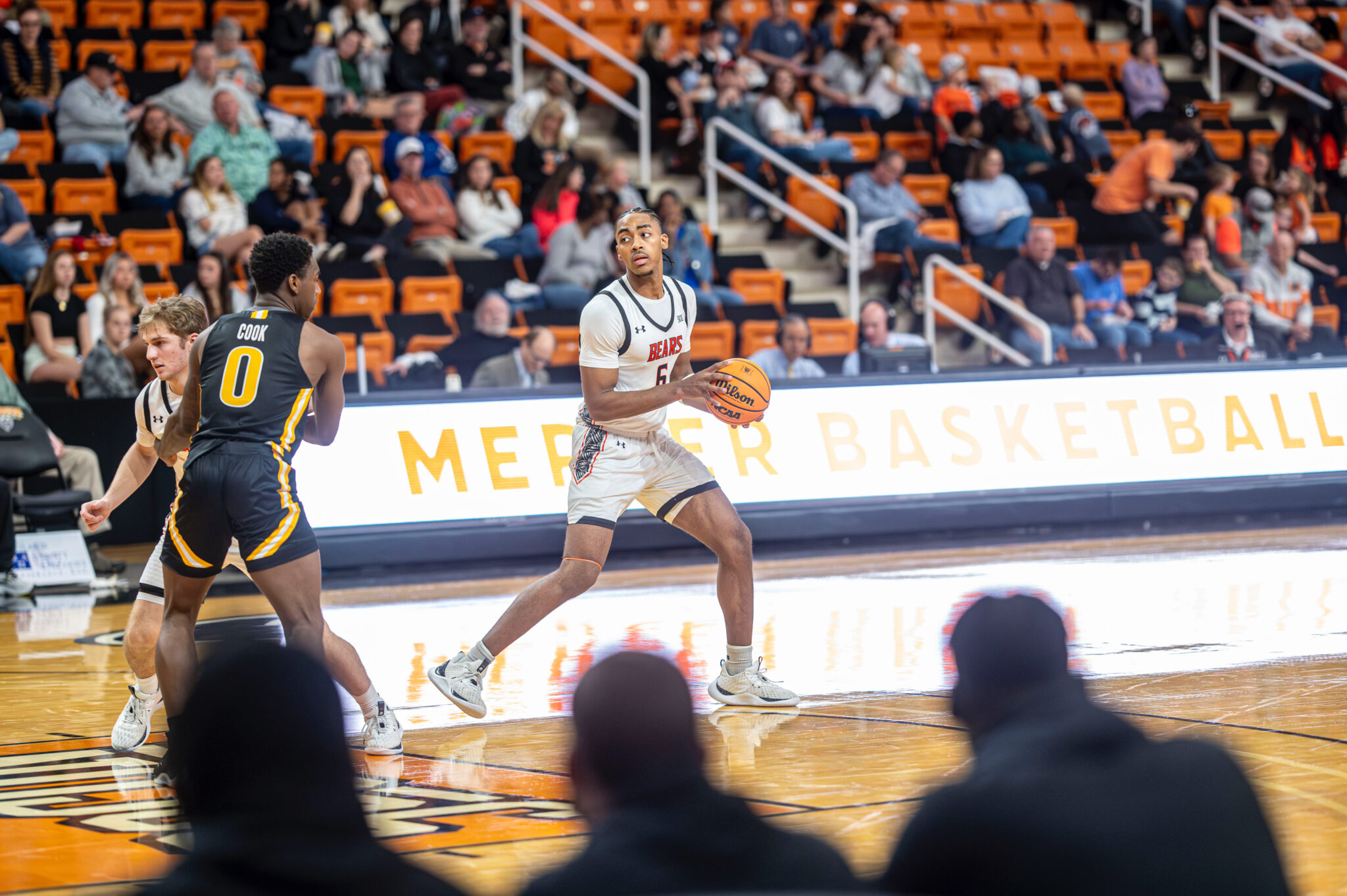 A Mercer basketball player dribbles the ball down the court during a game.