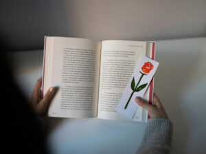 An open book and a bookmark with the drawing of a rose on it.