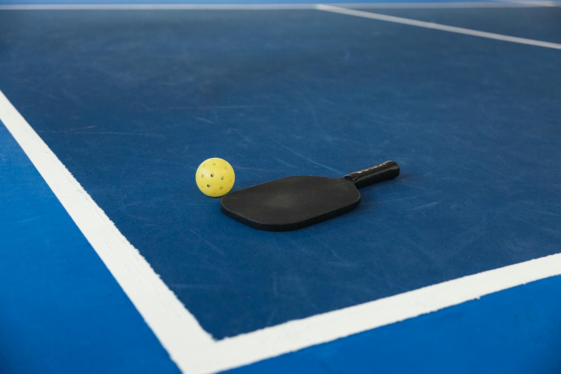 Pickleball paddle and ball on court.