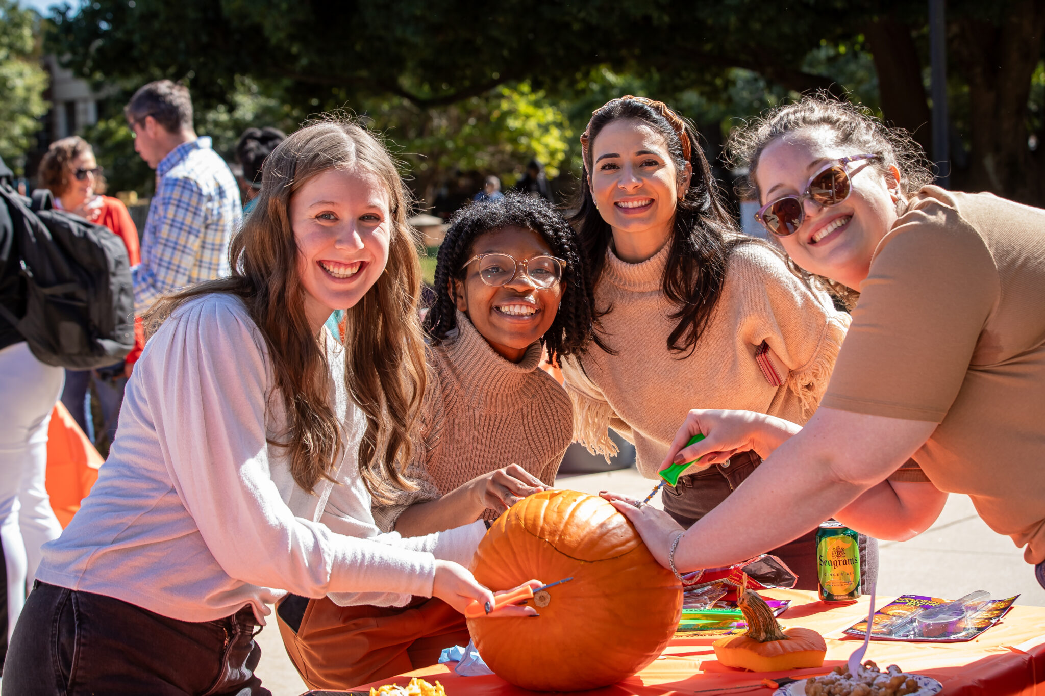 Four smiling people carve a pumpkin.