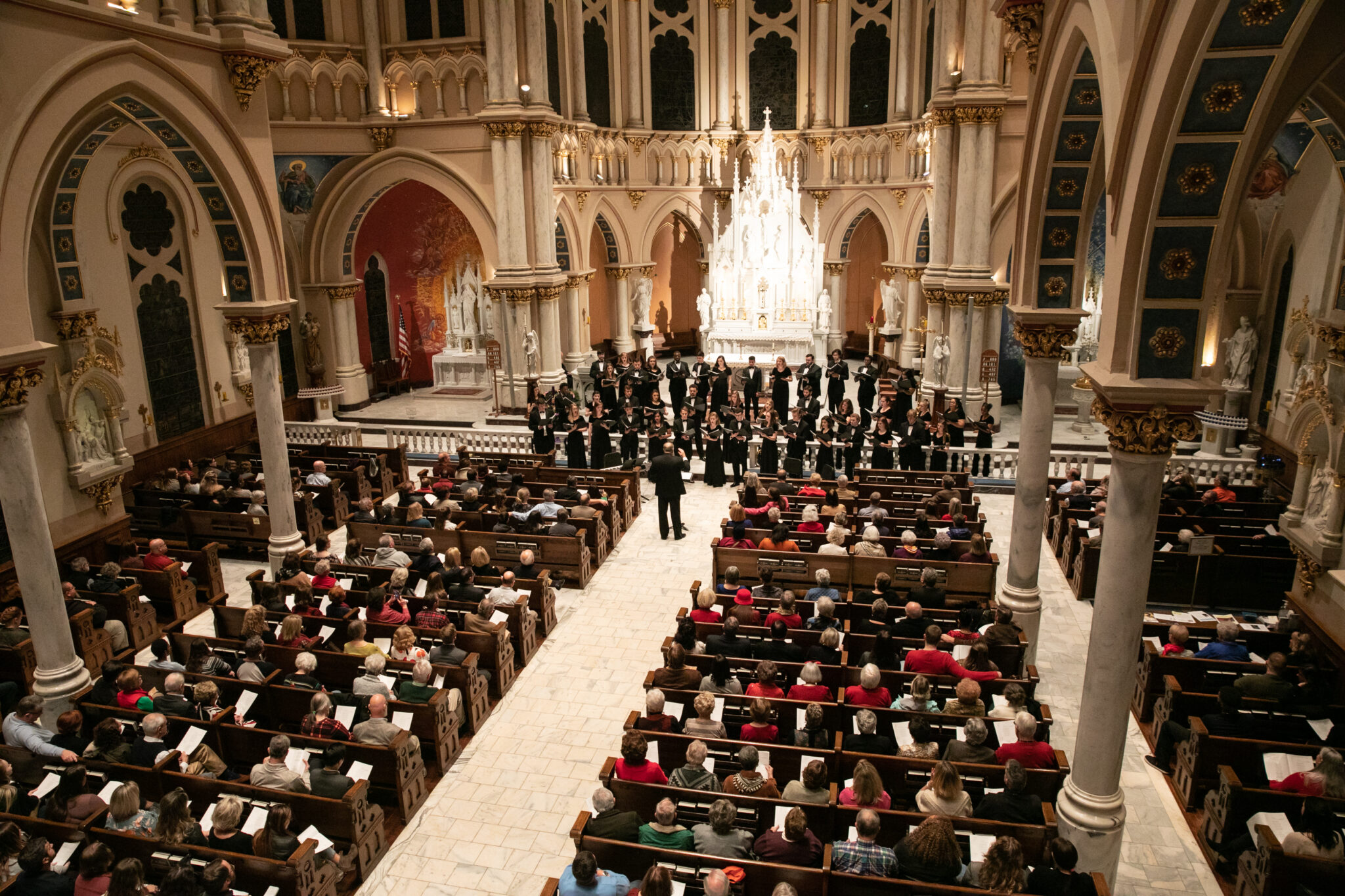 A choir performing to an audience in the ornate interior of a cathedral.