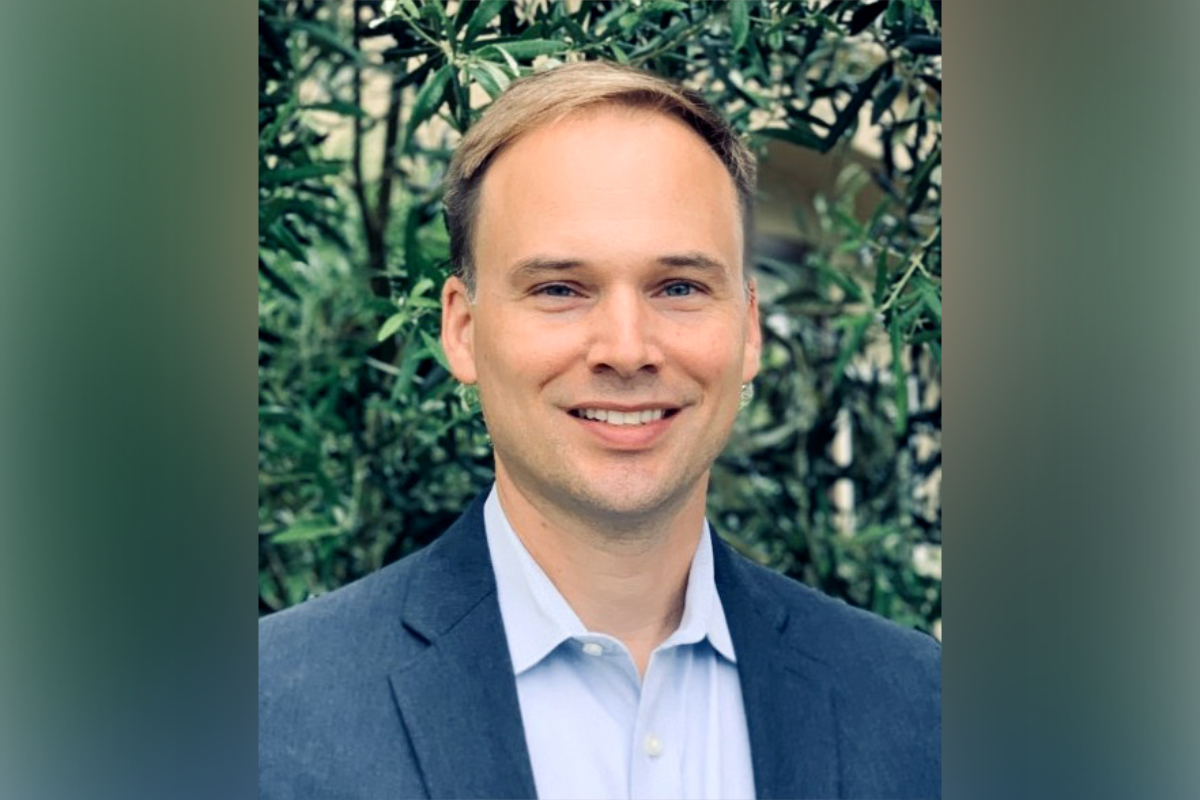 Headshot of Dr. John Compton wearing a blue jacket and light blue button down shirt.