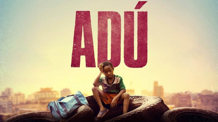 Movie poster for "Adu" featuring a sad-looking child sitting on a tire with a cityscape in the background.