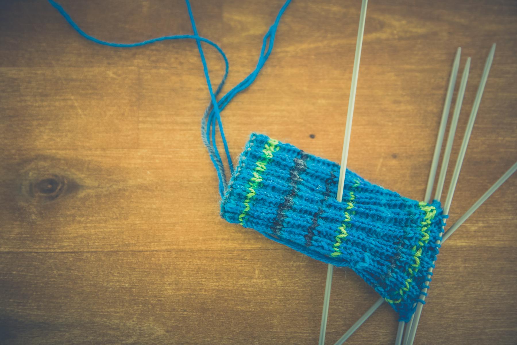 Blue knit textile on knitting needles