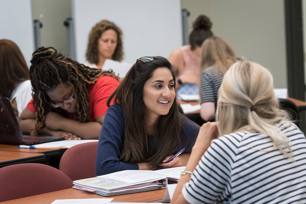 Mercer students engaging in a discussion while seated at tables during a classroom session.