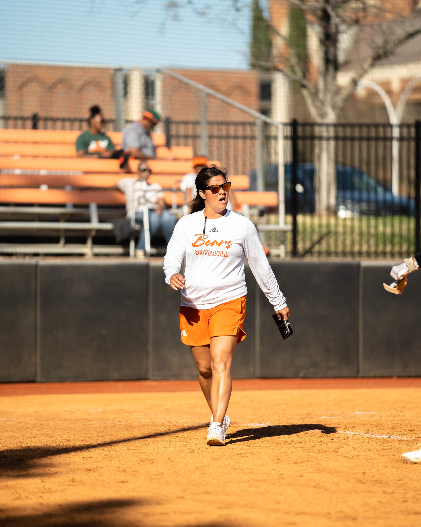 A woman walks on a softball field.