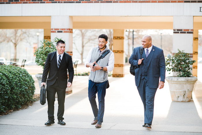 Three professionals walking outside in business attire.