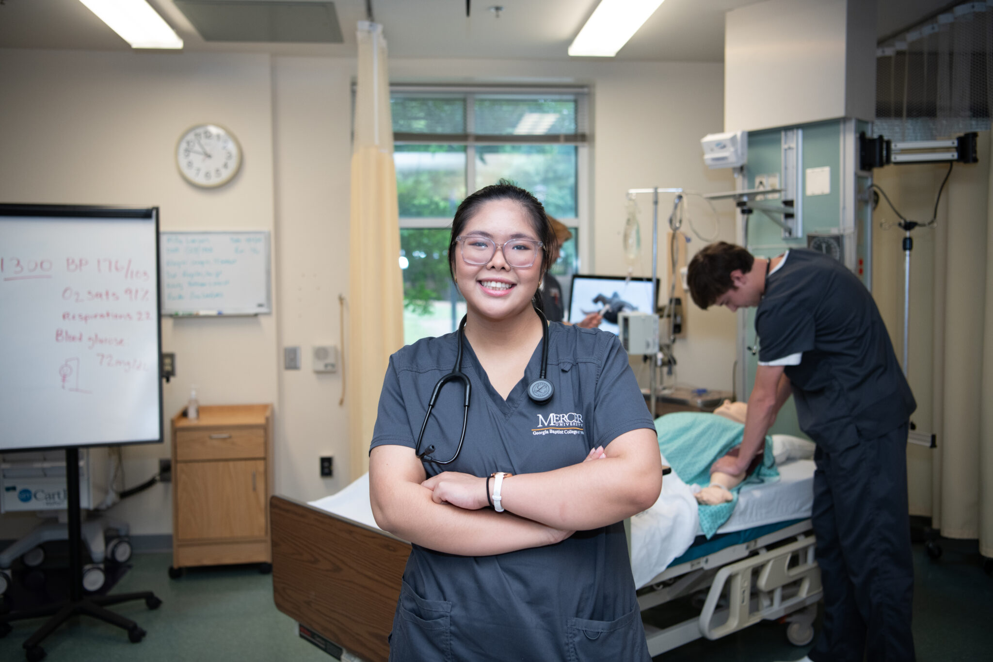 A nursing student stands in a simulation lab.