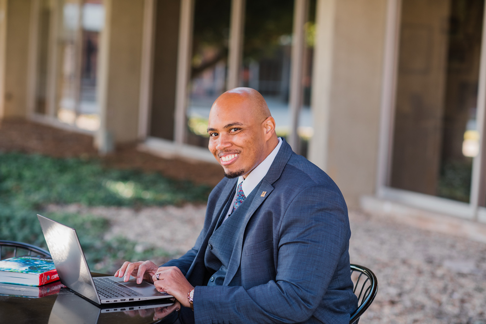 A Mercer student sits at an outside table working on a laptop.