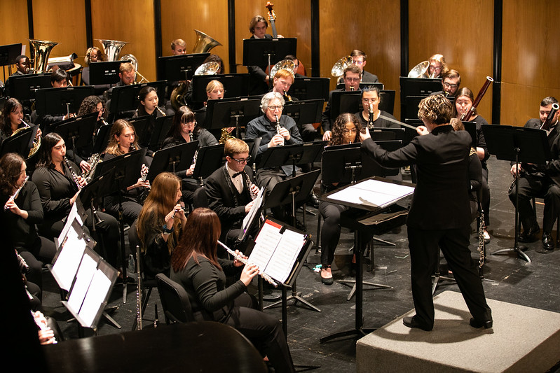 A wind ensemble performs on stage.