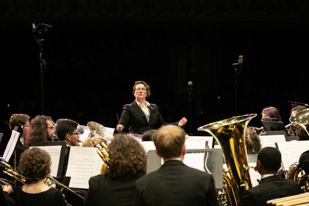 A conductor leading an orchestra performance on stage.