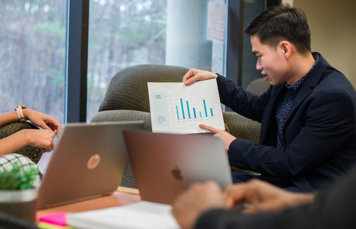 A man holds up a chart in a business meeting.