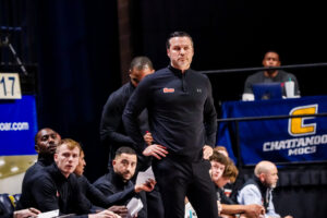 Mercer men's basketball coach Ryan Ridder stands on the sidelines during a game.