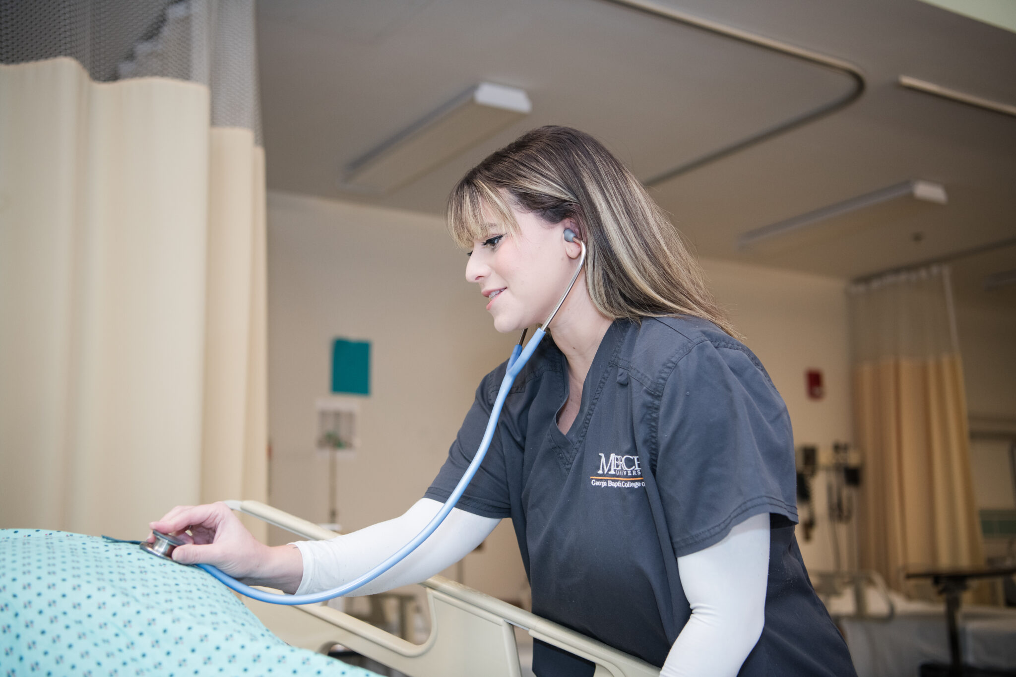 A nursing student uses a stethoscope.