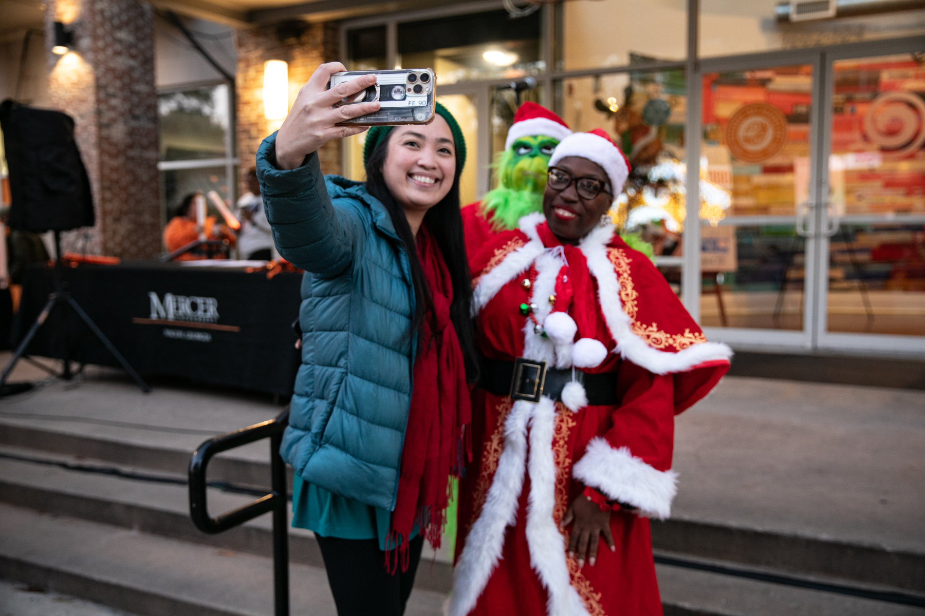 A student takes a selfie with Mrs. Claus and the Grinch in Mercer Village.