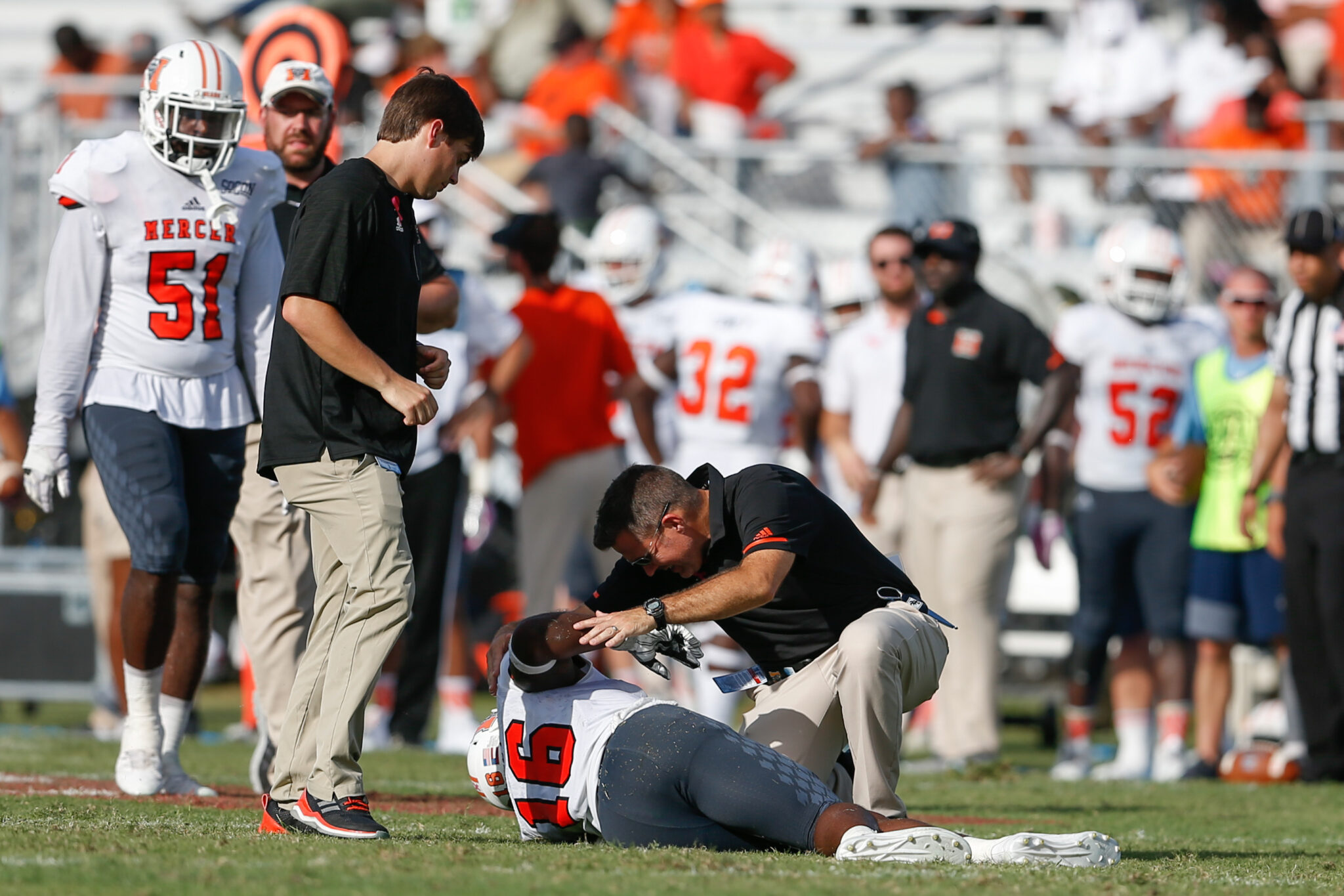 A trainer attends to an injured football player on the field.