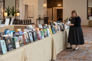 A woman picks up a book from a table with books on display.