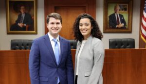Two law students stand in a courtroom
