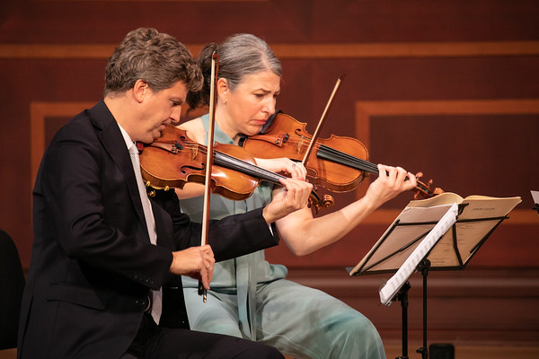 Two violinists perform on stage.