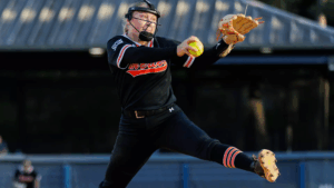 Mercer softball pitcher in mid-pitch, holding a yellow softball, with one leg raised.