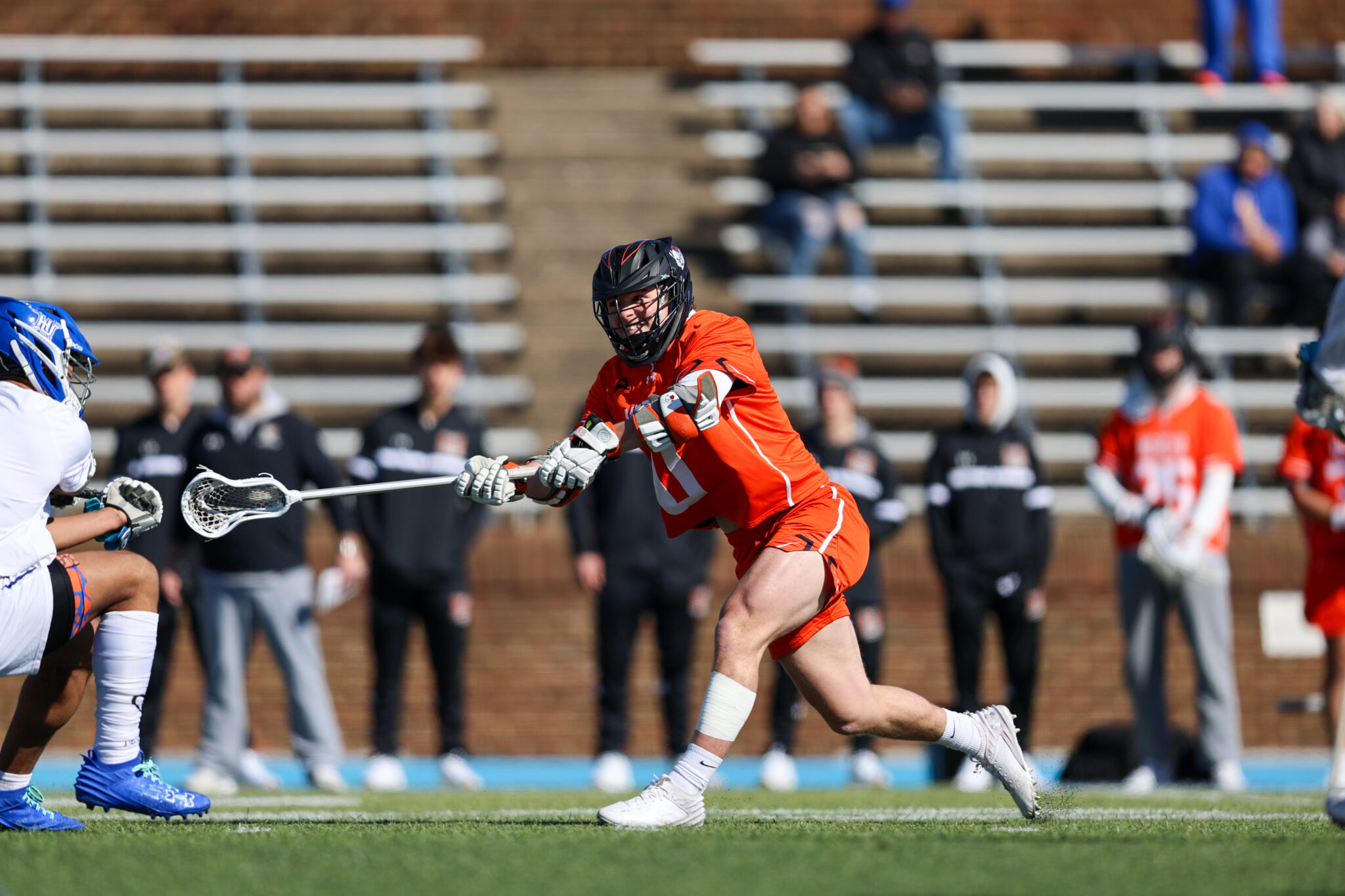 Mercer lacrosse player takes a shot while being defended by a player in white on an outdoor field.