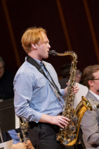 A musician plays the saxophone on stage.