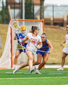 A Mercer lacrosse player is defended by a player in blue during a game.