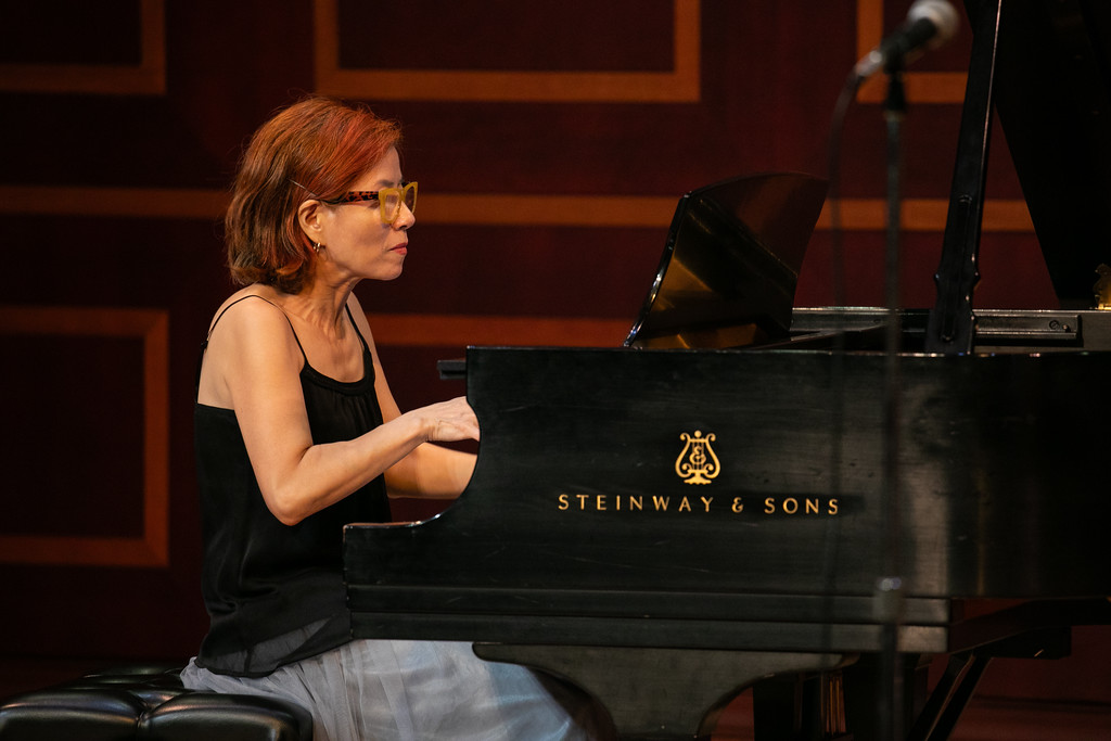 Person playing a grand piano on stage.