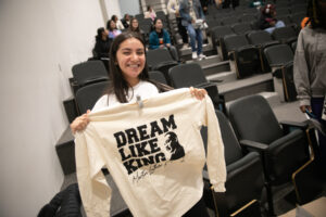 A Mercer student holds up a long-sleeved T-shirt that says Dream Like King and includes and image of Martin Luther King Jr.