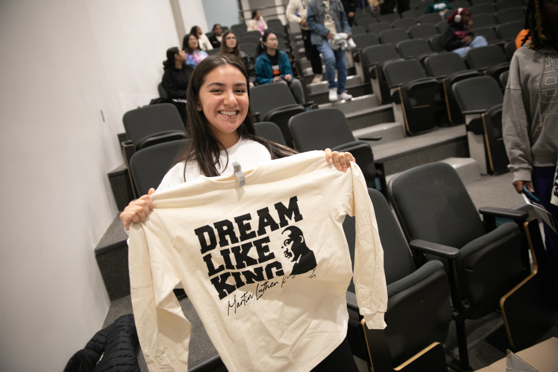 A Mercer student holds up a long-sleeved T-shirt that says Dream Like King and includes and image of Martin Luther King Jr.