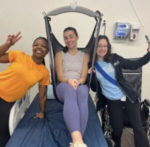 Three Mercer University students around a hospital bed.