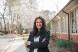 A woman stands outside next to a building.