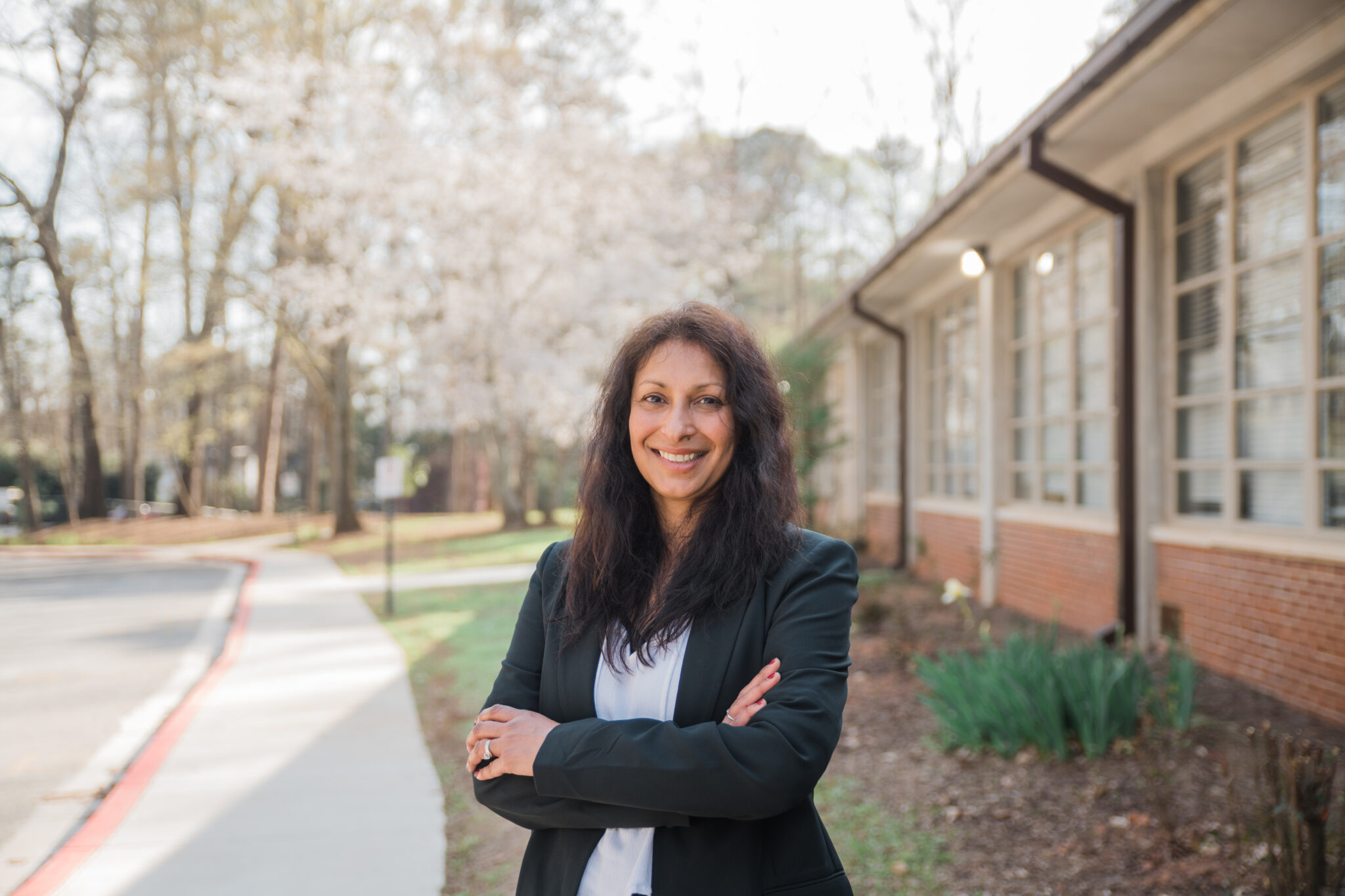A woman stands outside next to a building.