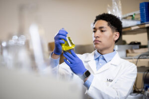 A Mercer student examines a beaker in a lab.