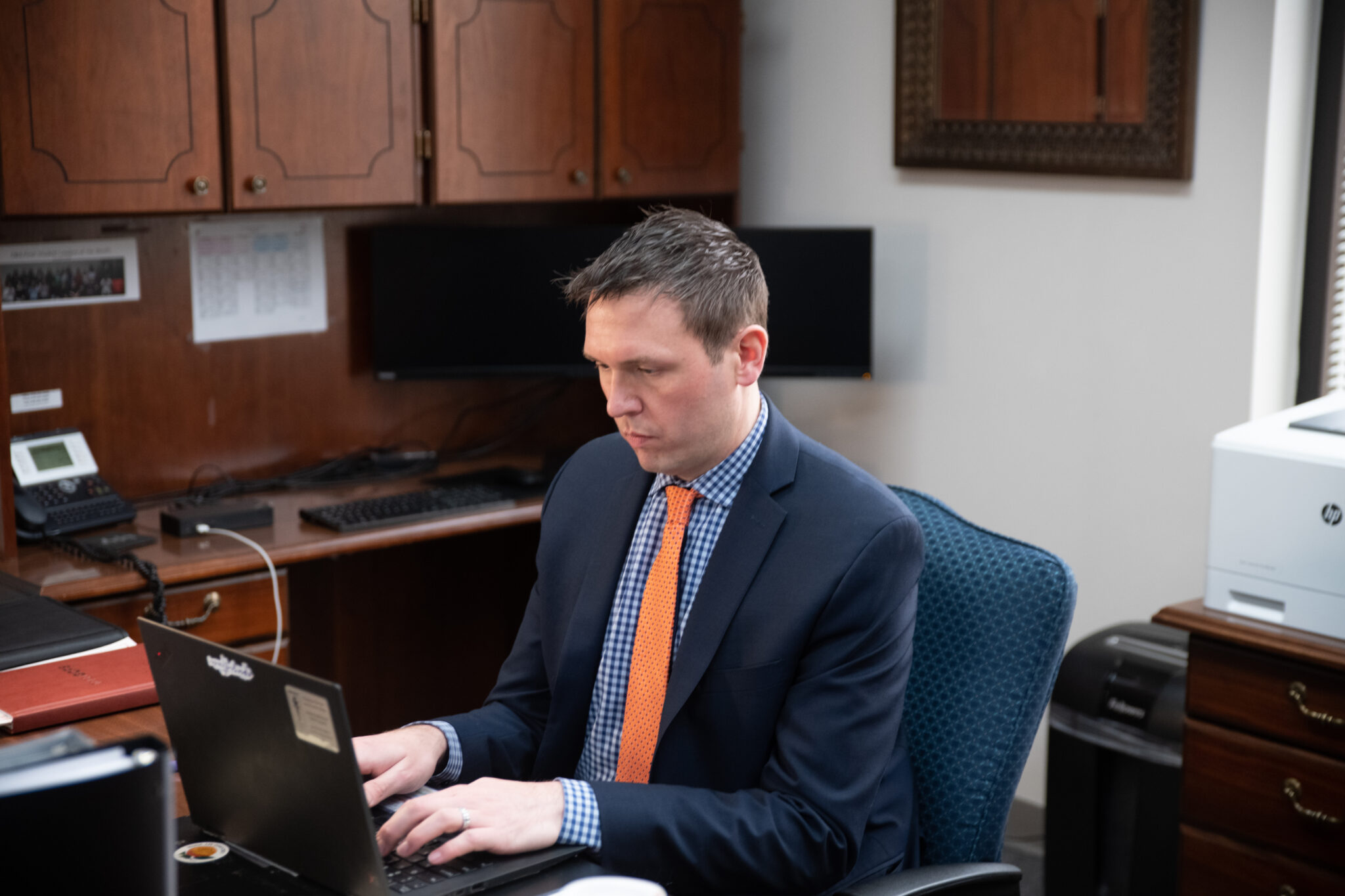 A man types on a computer at an office desk.