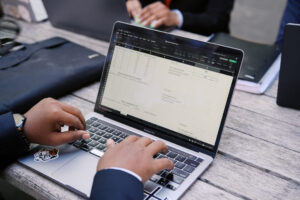 Person typing on a laptop displaying a spreadsheet.