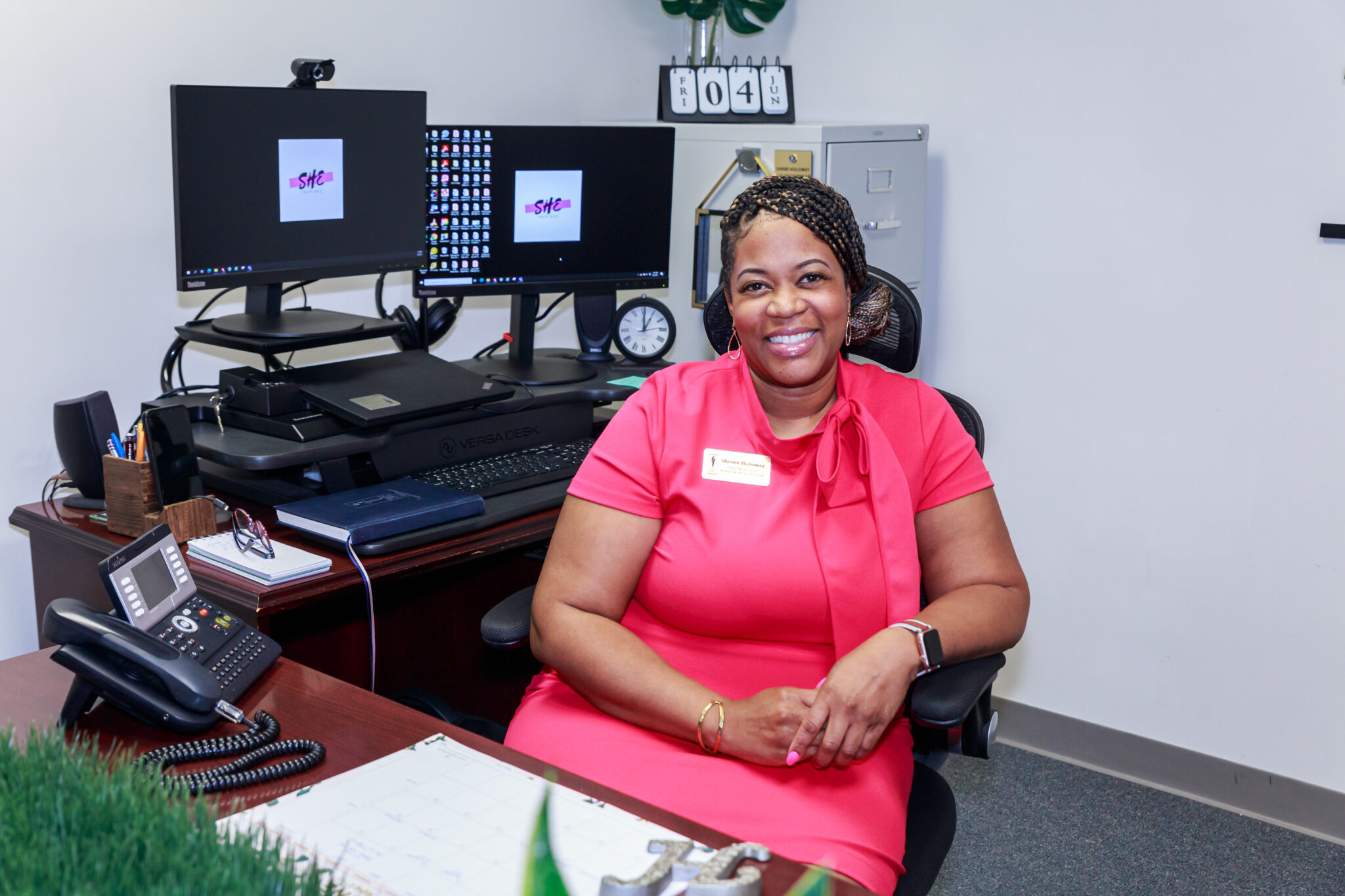 A woman sits behind an office desk.