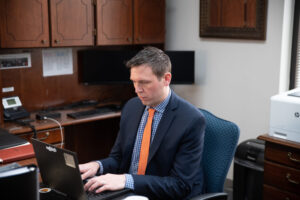 A man types on a computer at an office desk.