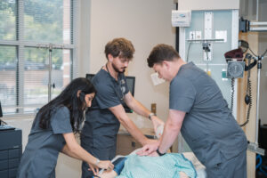 Three nursing students work on a mannequin.